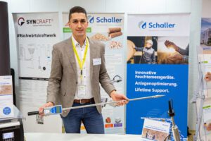 Florian Postl with a humimeter BLL Measuring device for wood chips in hand. At the booth at the heating plant operator day